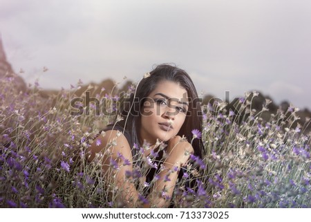 Portrait of a young brunette girl in a field of wild flowers