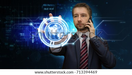 Young businessman touching media icon on digital screen in virtual office while talking on his mobile phone. Futuristic work concept. 