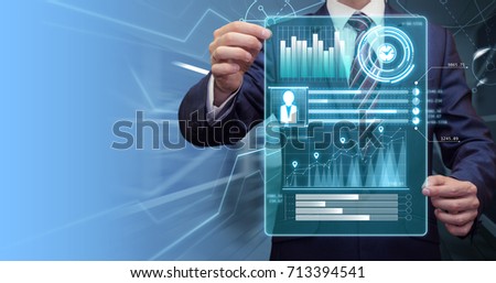 Close up of businessman holding virtual panel with financial graphs in his hands. Modern business concept. Futuristic background. Copy space for your text.