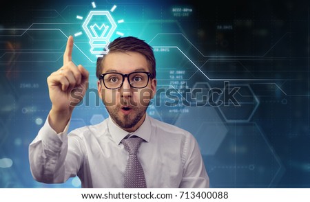 Young office worker with amusing excited face expression holding his index finger up showing he has new idea. Futuristic background. Copy space for your text.
