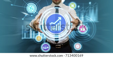 Young businessman making presentation in his futuristic office touching virtual panel with media and financial graphs. Modern business and technology concept.