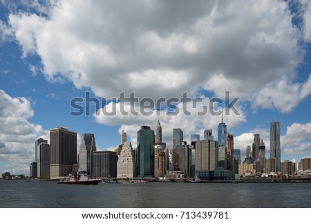 Lower Manhattan skyline across the East river in a hot summer day, bright light cloudy blue sky, New York City.