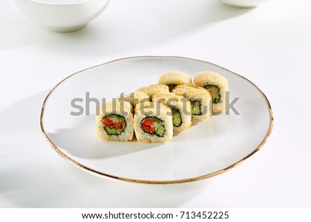Hot roll with cucumber, Bulgarian pepper rice and greens breaded on white plate with gold border. Asian restaurant menu