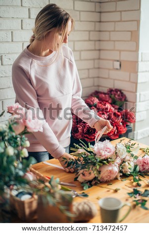 hands of florist against desktop with working tools and ribbons on wooden background