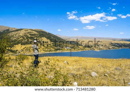A curious traveler in a hat is takes pictures a storage reservoir
 in Armenia.