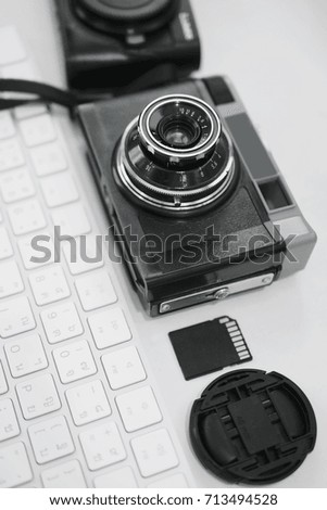 Top view Black and White Retro classic film camera and digital camera white keyboard memory card lens cap on the white desk table