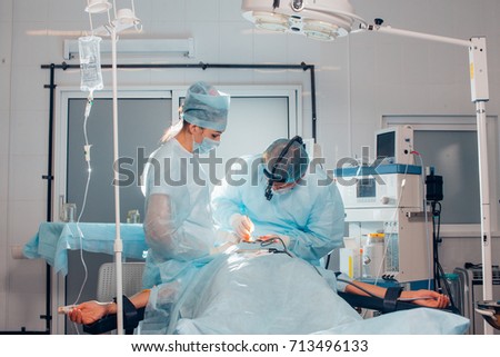 Surgeon performing cosmetic surgery on nose in hospital operating room. Surgeon in mask wearing surgical loupes during medical procedure. nose augmentation, enlargement, enhancement