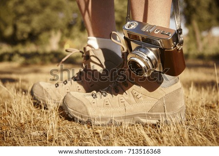 Vintage camera with hiking boots on the ground. Travel background