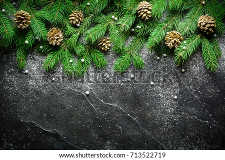 Christmas and New Year background. Christmas tree branch on a black background. Cones and fur-tree toys. View from above. Copy space.