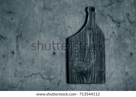 Handmade burned cutting board on a wooden rustic texture for background. Rough weathered wooden board. Toned.