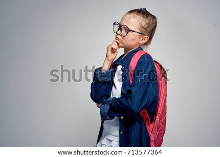 school, teaching, education, sad schoolgirl with glasses on his shoulders pink backpack on a gray background                               