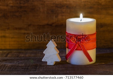 Christmas card background. Christmas tree and burning candle with red ribbon bow on wood with copy space.