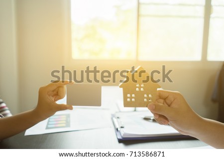Business man holding house representing home ownership and the Real Estate business, money and stack of coins,interface smart home assistant on a virtual screen for buying new house with credit card