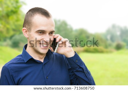 man, using, smart phone, in the hands, stand in the park, background with copy space