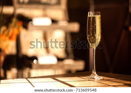 Shot of the champagne glass on a wooden table. Sunlight and bubbles. Royalty-Free Stock Photo #713609548