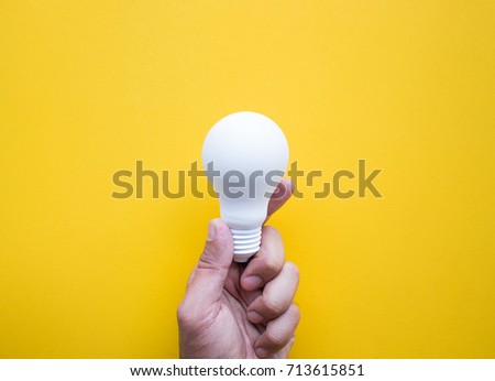 Human hand holding white lightbulb on pastel color background.Ideas creativity,inspiration,concepts.Flat lay design.