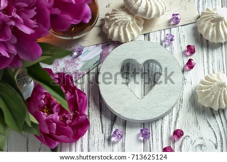 Peonies flowers pink glass of tea with white wooden heart marshmallow on a white wooden background - stock image