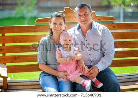 Grandparents and granddaughter sit on a swing, embrace and smile