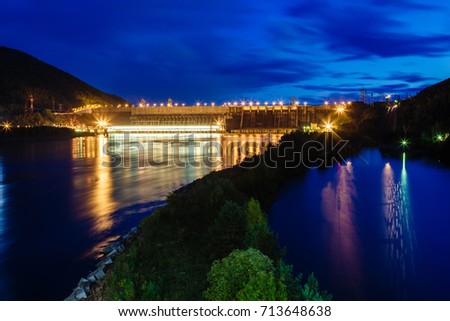The dam of hydroelectric power station in twilight lit with lamps, night, the picture on long endurance