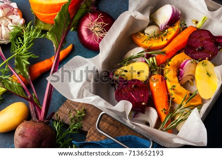 Preparing  roasted vegetables with garlic and herbs on the baking tray. Autumn-winter root vegetables. Royalty-Free Stock Photo #713652193