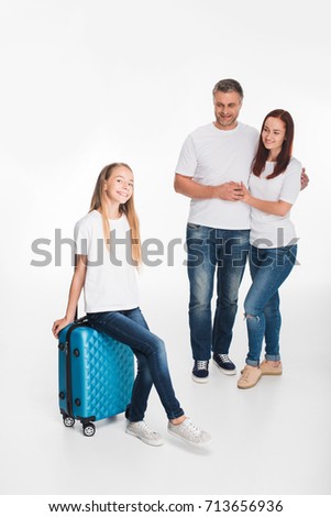 happy young family of tourists hugging and holding luggage, isolated on white 