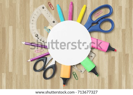 Close up of school supplies under an empty round paper on the wooden floor 
