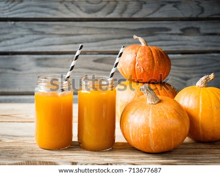 Pumpkins juice in bottle with pumpkins on wooden background. Copy space.