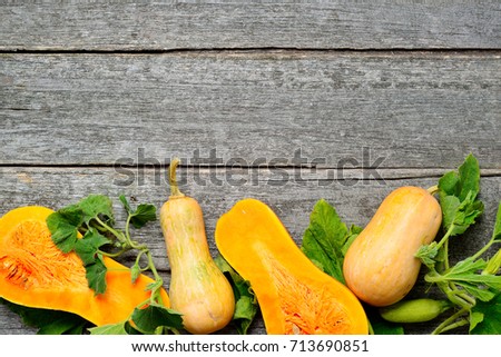 Pampkin and zucchini with green leaves on vintage wooden table. Autumn harvest background