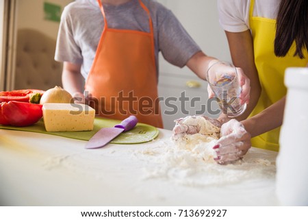 Photography of cook woman who kneading the dough and her son helping hers