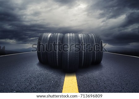 Five black tires rolling on a road with clouds Royalty-Free Stock Photo #713696809