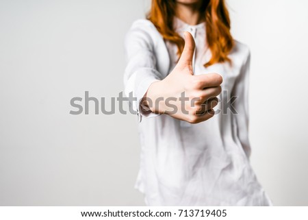 A young girl with red hair lifts her finger, shows that she is happy. Isolated on white background