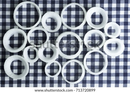 Fresh raw onion rings, against the background of checkered tissue