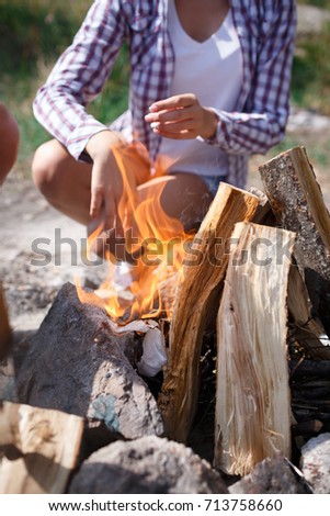 Female camper kindling to start a campfire, bonfire close-up. Man kindles a fire. Fire in nature. Bonfire in the forest.