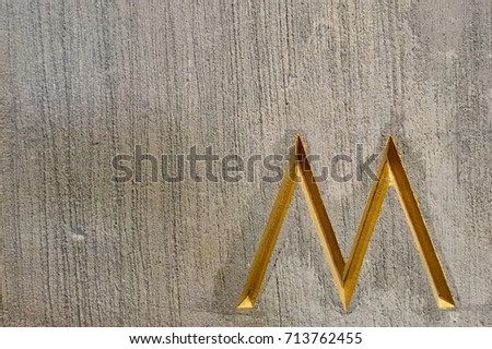 Yellow or Gold Alphabet 'M' on Cement Background  Royalty-Free Stock Photo #713762455