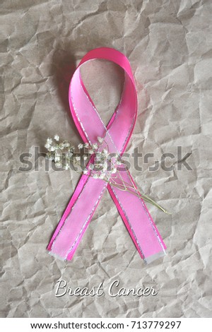 Vertical postcard for National Breast Cancer Awareness Month with pink and transparent ribbons with sprig of little white florets on the kraft paper with text.