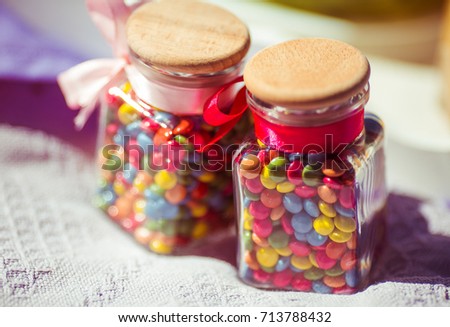 Bottles with colorful candies on white plaid