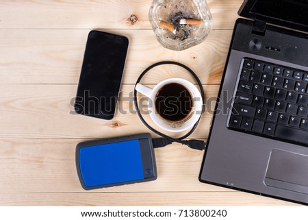 Flat lay above lap top computer on the wooden table with external hard disc hdd mobile phone cup of coffee and ashtray and with copy space.