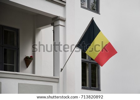 Belgium flag. Belgian flag displaying on a pole in front of the house. National flag of Belgium waving on a home hanging from a pole on a front door of a building.
