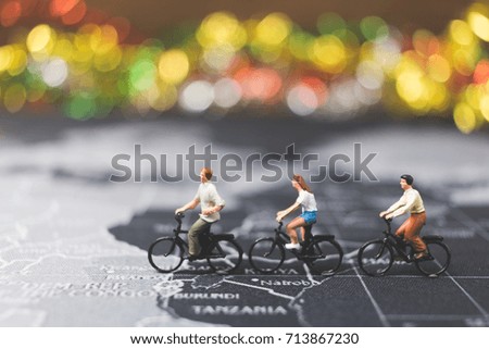 Miniature people travelers riding bicycle on world map , Traveling and exploring the world Concept