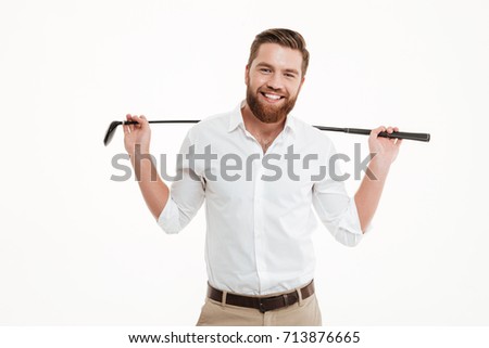 Picture of cheerful young bearded man standing over white wall background isolated holding golfstick. Looking camera.
