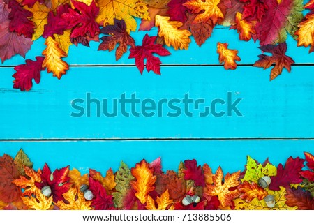 Colorful fall leaves border on blank antique rustic teal blue wood background; autumn, Thanksgiving, Halloween, seasonal nature sign with painted copy space