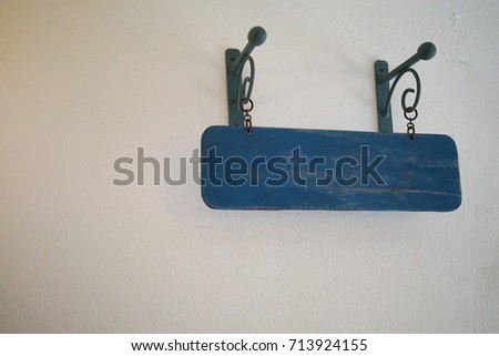 The blue wooden doorplate is hung on the white wall. 