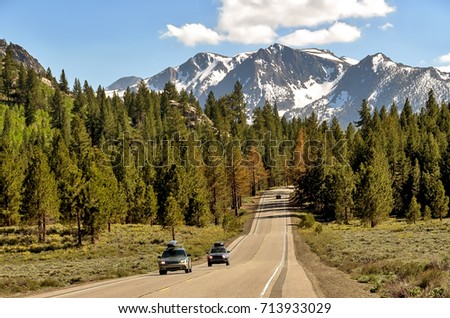 Cars traveling on California highway with snowy Sierra Nevada mountains background