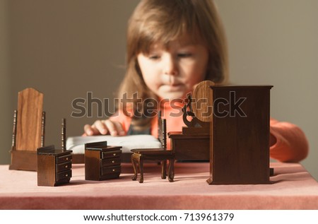 Little girl playing with doll house furniture