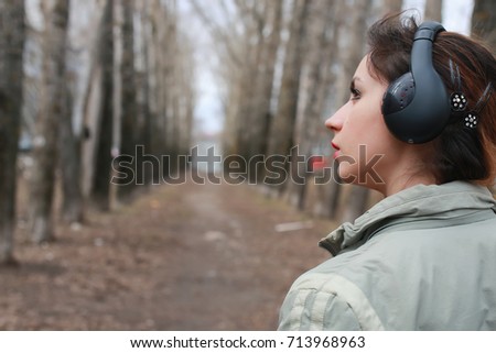 woman with headphones in park autumn