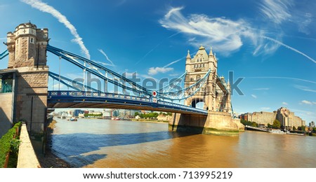 Panoramic image of Tower Bridge in London on a bright sunny day with feather clouds.
