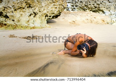 Young woman at swimsuit taking picture on Jimbaran beach, Bali, Indonesia