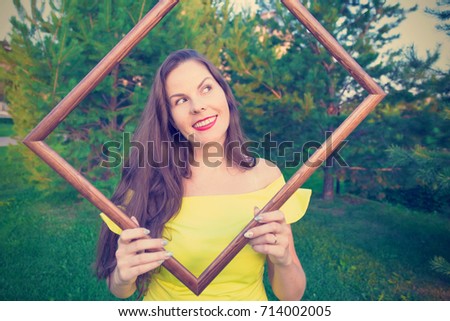 Young woman holds picture frame in hands and smiles