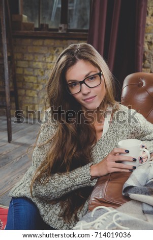 Portrait of beautiful woman in eyeglasses with cup of hot drink. Posing and smiling