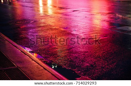 Lights and shadows of New York City. NYC streets after rain with reflections on wet asphalt. Silhouettes of people walking on the street